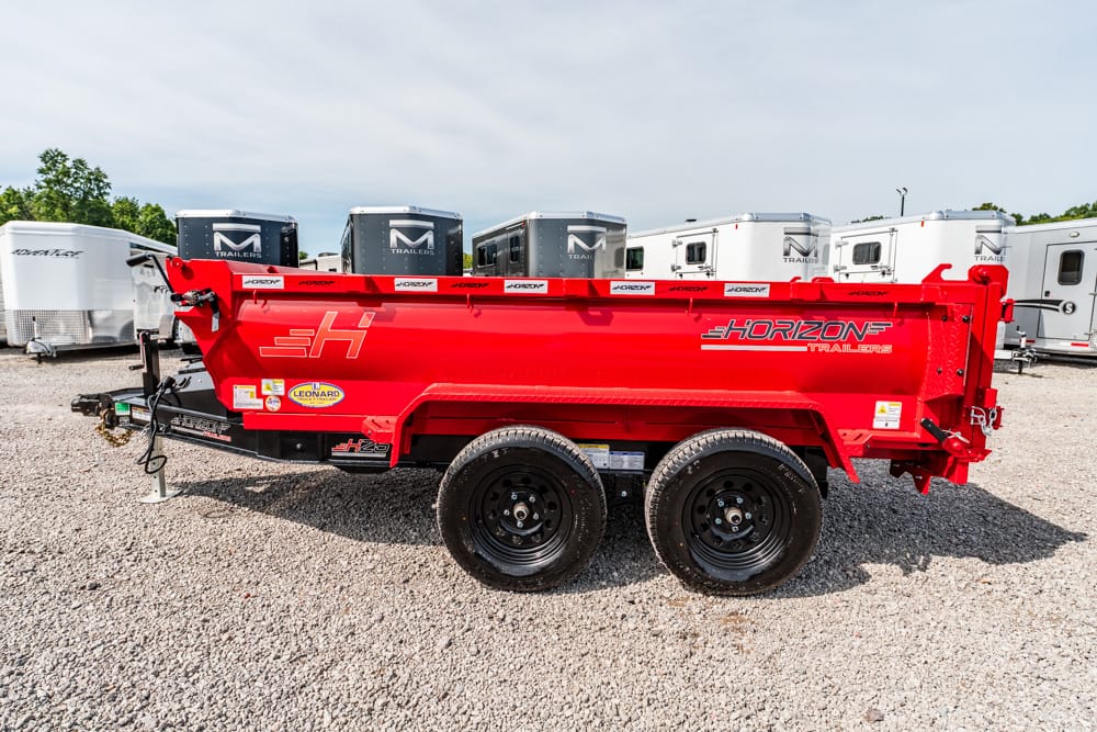 Red Horizon dump trailer with dual axles parked on a gravel lot beside other trailers