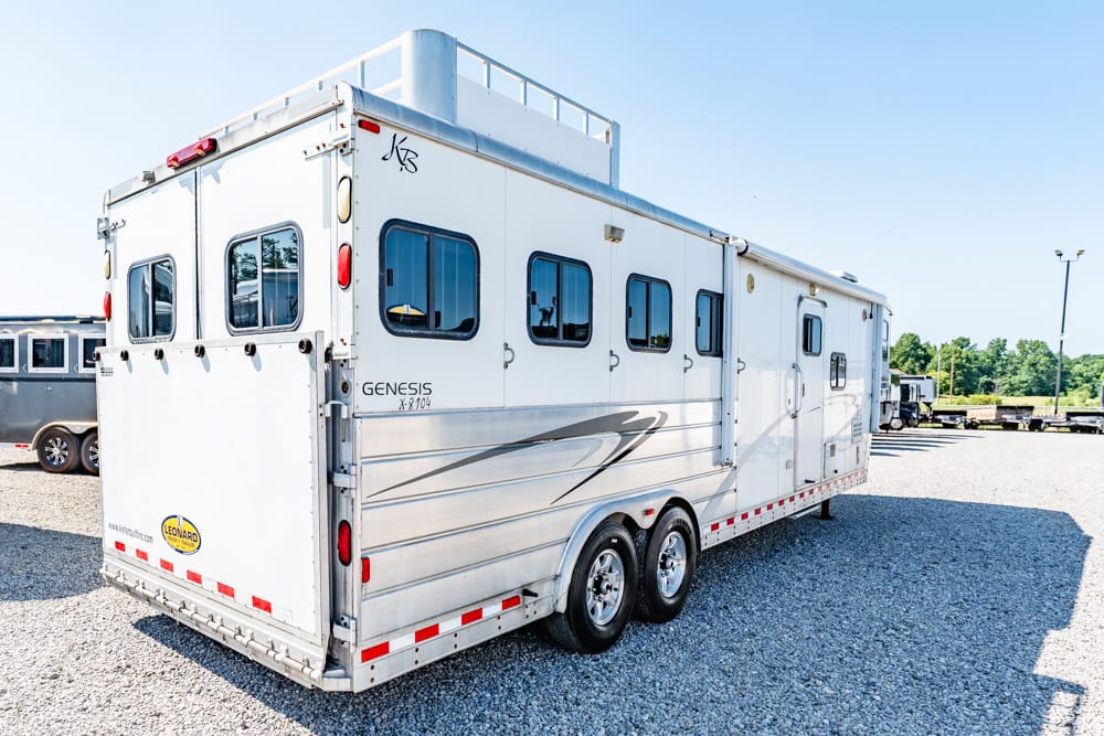 White Genesis horse trailer with two axles parked on a gravel lot, side view with windows and doors visible.