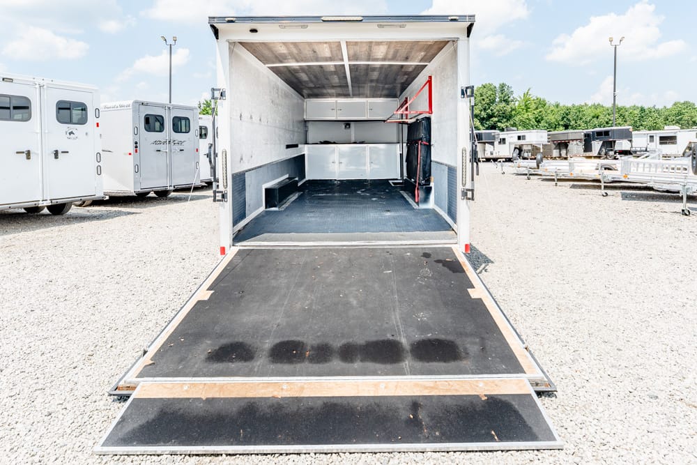 Open enclosed trailer with ramp down, empty cargo space and built-in cabinets along the far wall.
