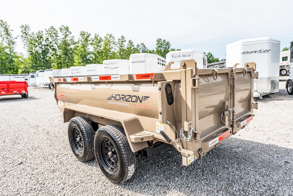 Tan Horizon trailers dual-axle dump trailer on gravel lot with white horse trailers in the background