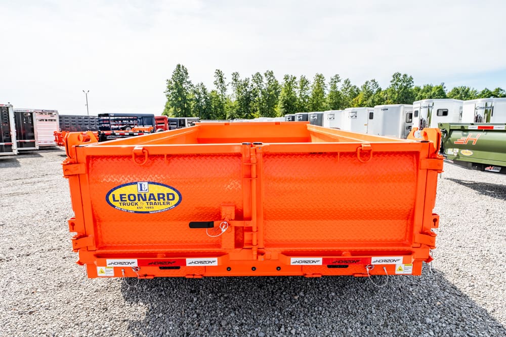 Bright orange dump trailer in a gravel lot with a Leonard Truck & Trailer logo on the side