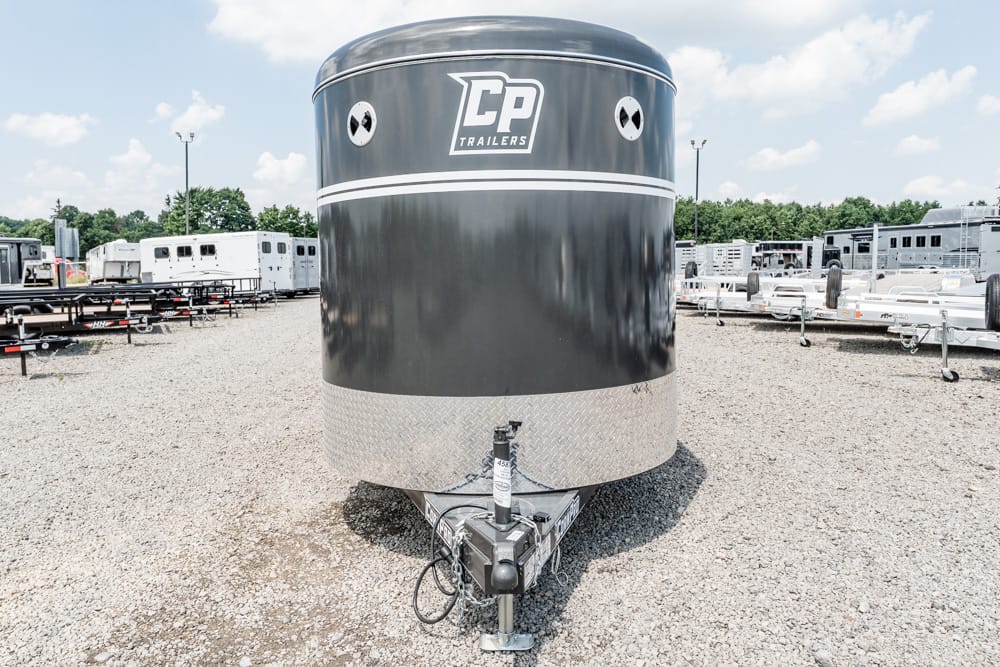 Front view of a black CP Trailers enclosed trailer with a diamond-plate lower edge, hitch visible at the front, parked in a gravel lot with other trailers nearby.