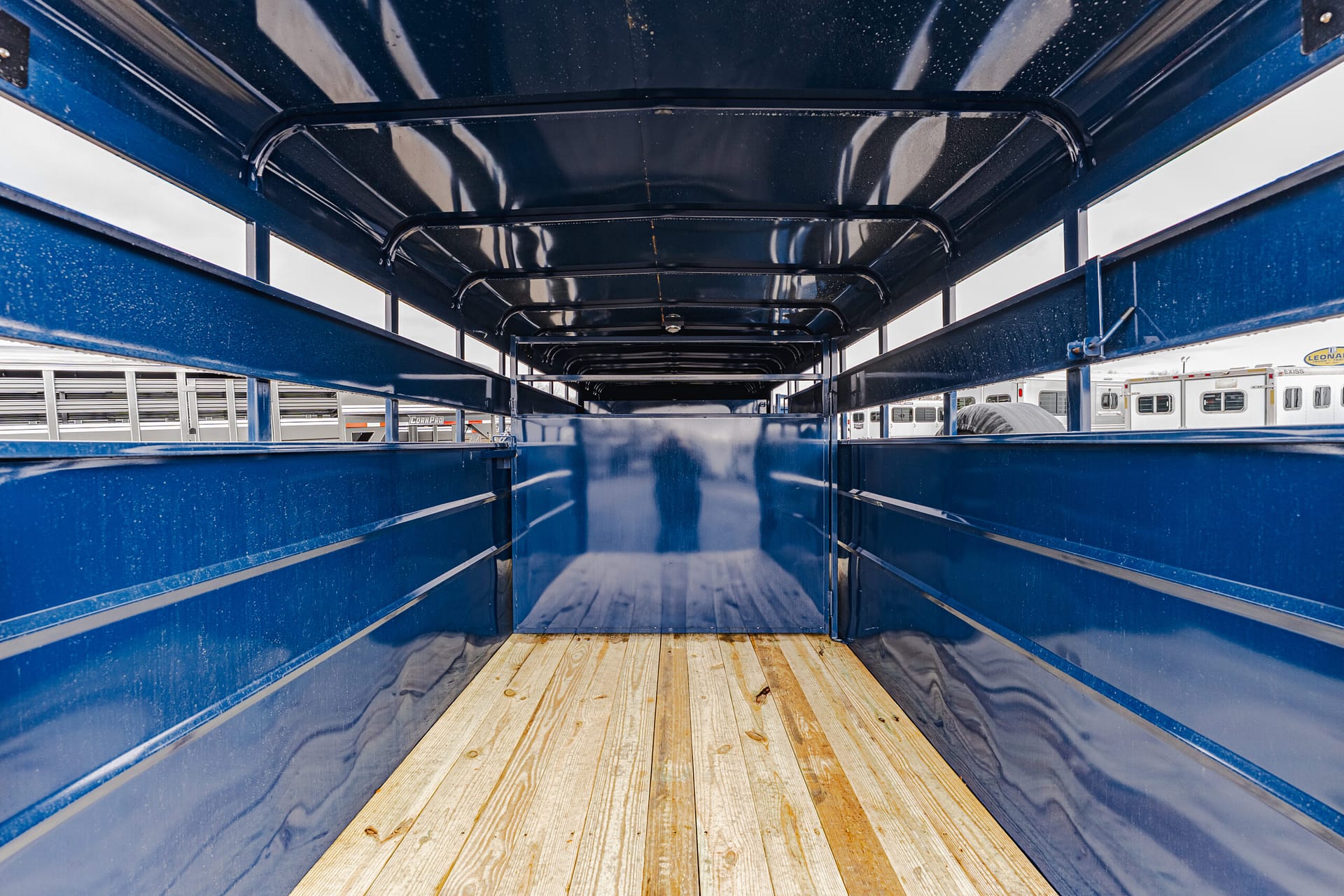 Inside view of a blue cargo trailer with a wooden floor, looking toward the far end