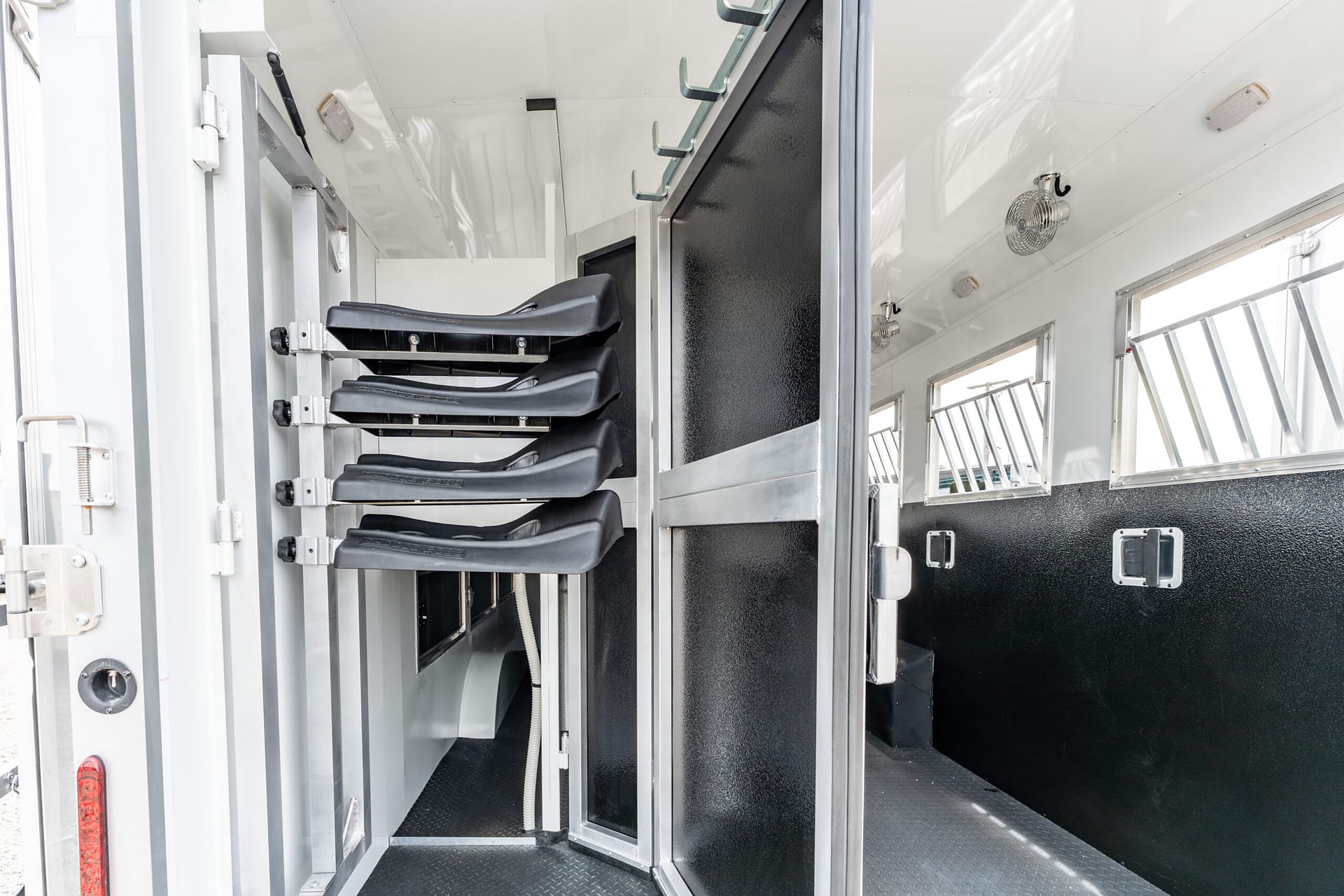 Interior of a metal trailer with black folding seats along a wall and vertical storage compartments.