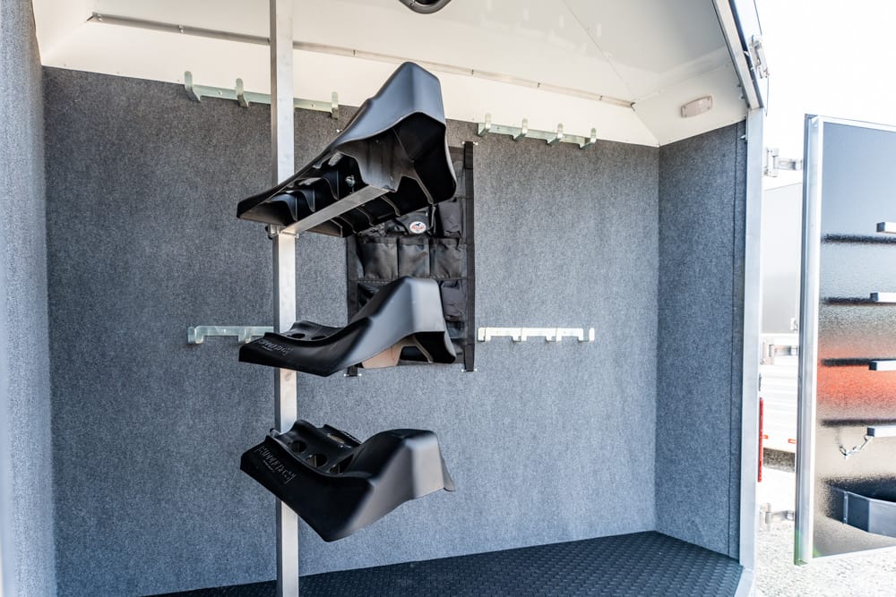 Interior of a trailer showing a vertical shoe rack with three black high heels on display.”,