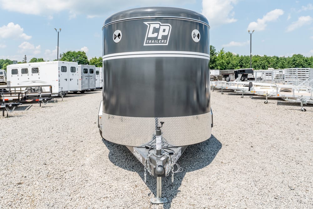 Front view of a black CP Trailers enclosed trailer with a diamond-plate front and hitch, parked on a gravel lot with other trailers in the background.