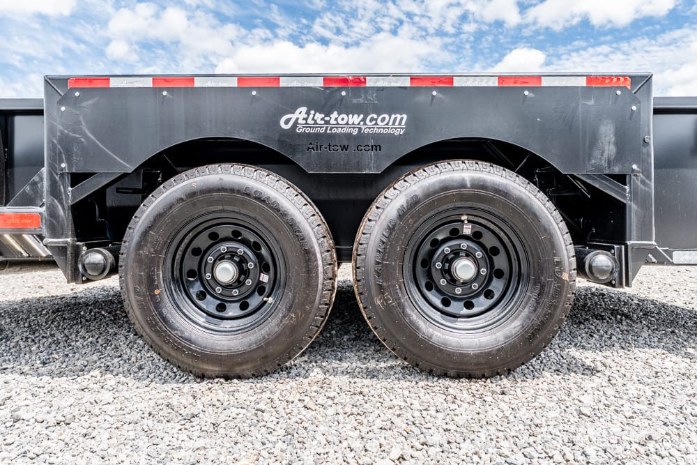 Dual rear wheels of a heavy dump trailer on gravel, with Air-tow branding visible on the side panel.