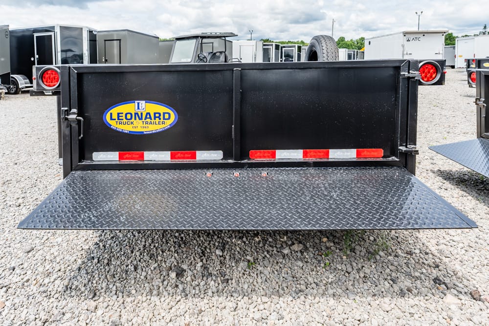 Rear view of a black dump trailer with a diamond-plate ramp lowered to the ground, Leonard Truck & Trailer logo on the side.