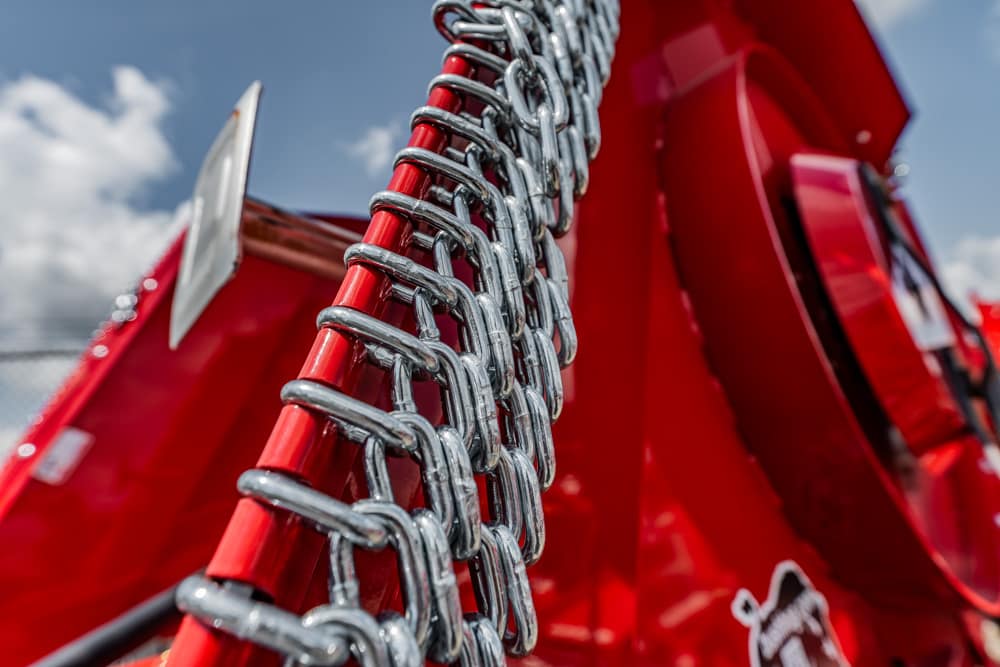 Close-up of heavy metal chains wrapped around a red industrial machine, with a blue sky in the background.