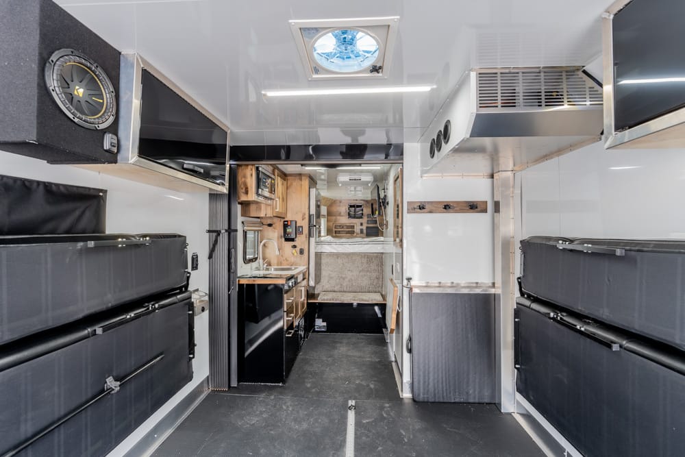 Interior of an ambulance with black padded benches along both walls, storage cabinets, and a narrow passage to the rear.