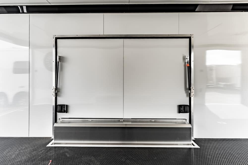 White double doors of a cargo trailer with a metal loading ramp extended at the bottom