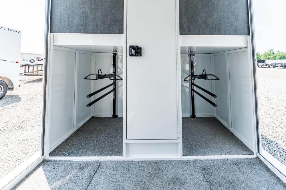 Two empty storage bays in a trailer with hanging rails and a central white cabinet in the middle.
