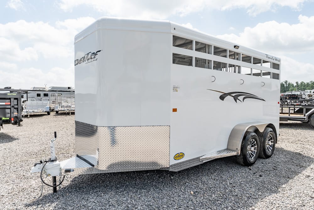 White horse trailer with dual axles and diamond-plate front on a gravel lot, showing vents and a tow hitch.
