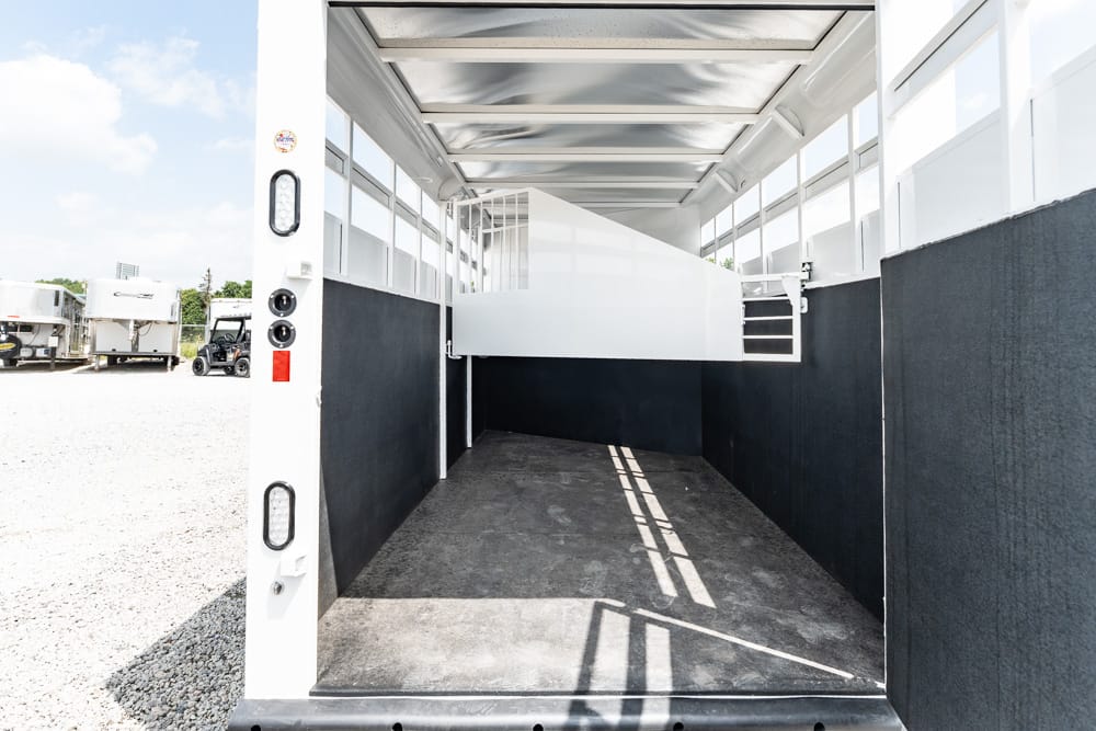 Inside of an empty white trailer with black lower walls and a raised white platform; gravel lot outside left side.