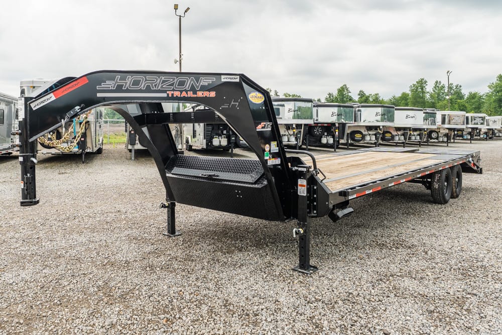 Black gooseneck flatbed trailer with a wooden deck, Horizon Trailers branding, parked in a lot with other trailers in the background.