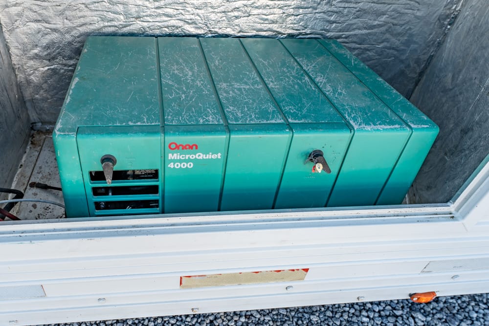 Green Onan MicroQuiet 4000 portable generator stored in a trailer trunk area