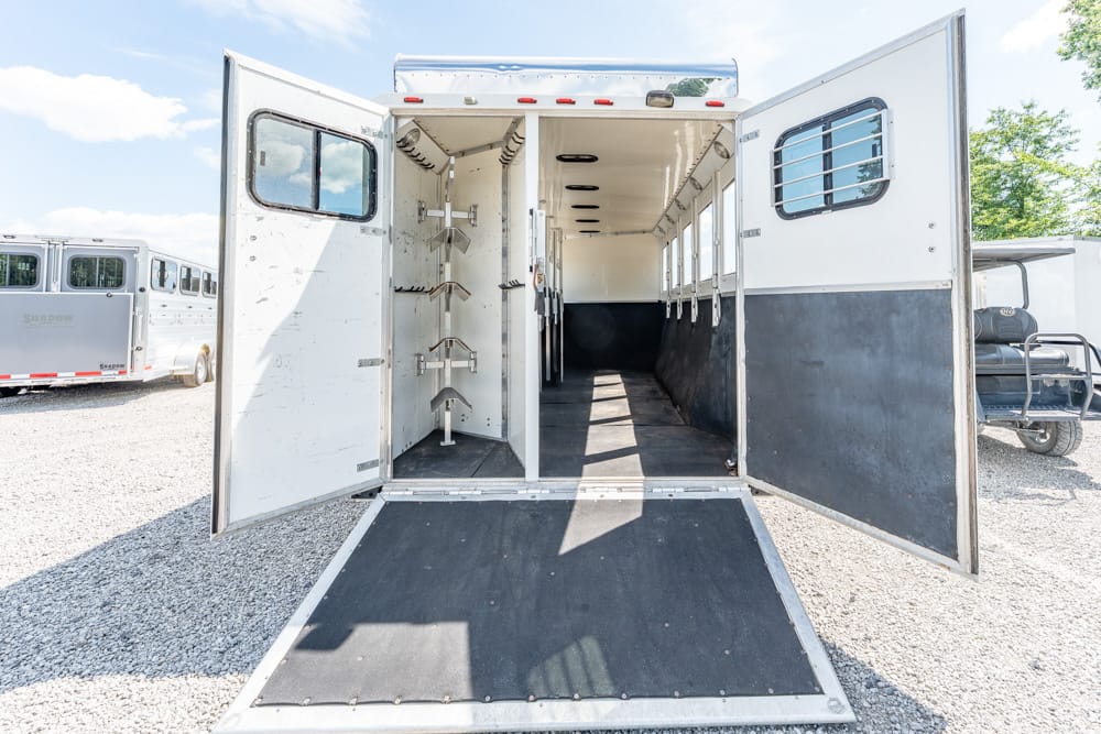 Open horse trailer with ramp down, interior stalls visible along the length.