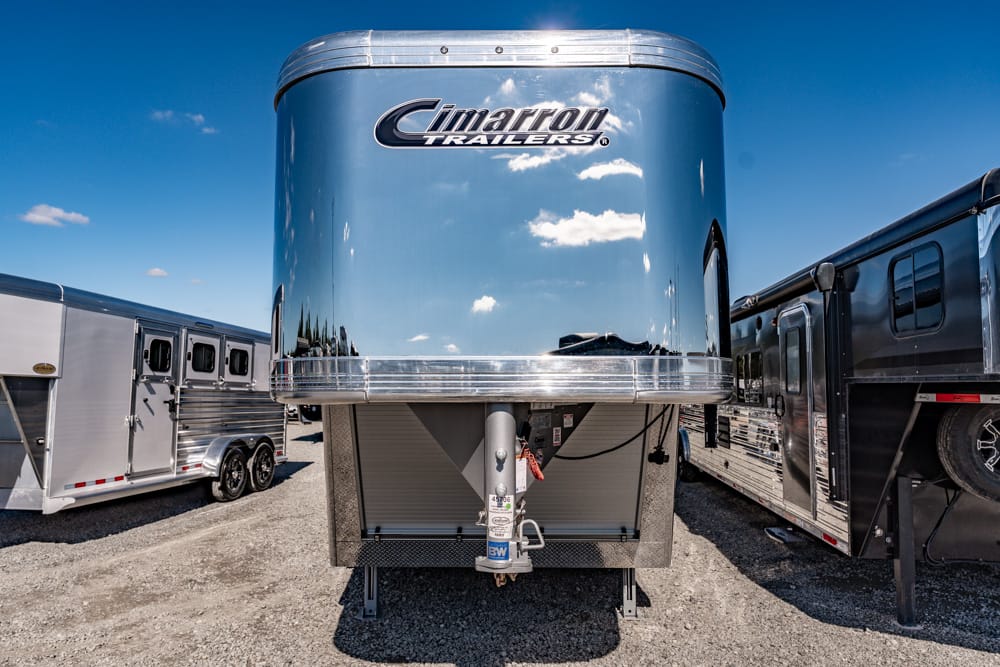 Front view of a blue Cimarron trailer in an RV lot, with other trailers visible on both sides.