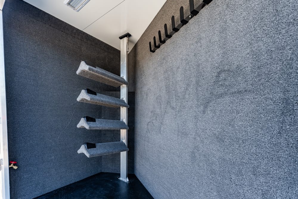 Soundproof booth with stacked angled foam panels on a vertical rail and wall hooks in a small studio room.