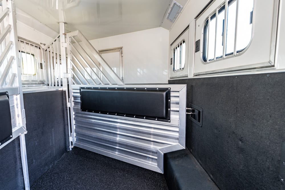 Interior of a metal horse trailer with dividing partitions and padded walls, ready for transporting horses