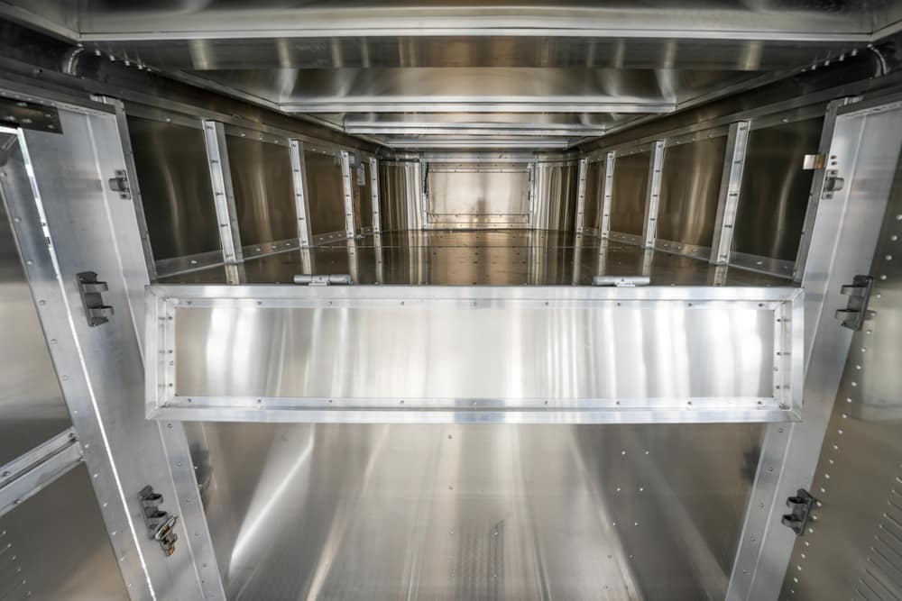 Interior view of a large stainless steel industrial enclosure with multiple rectangular bays and metal framing.",