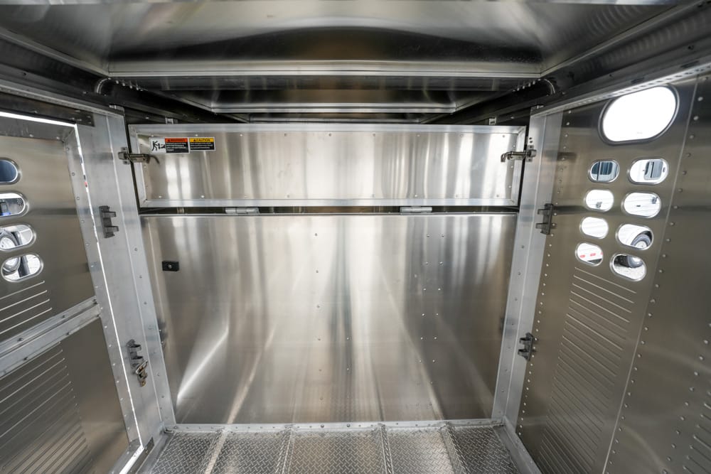 Interior of a metallic aircraft cargo hold with riveted stainless steel walls and a metal floor.