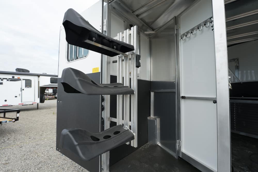 Inside of a horse trailer showing three fold-out black plastic steps for entry.