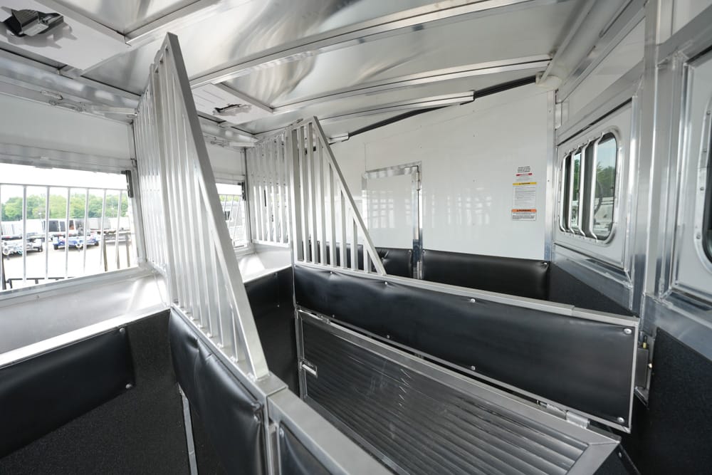 Interior of a metal horse trailer with divider stalls and black padded walls