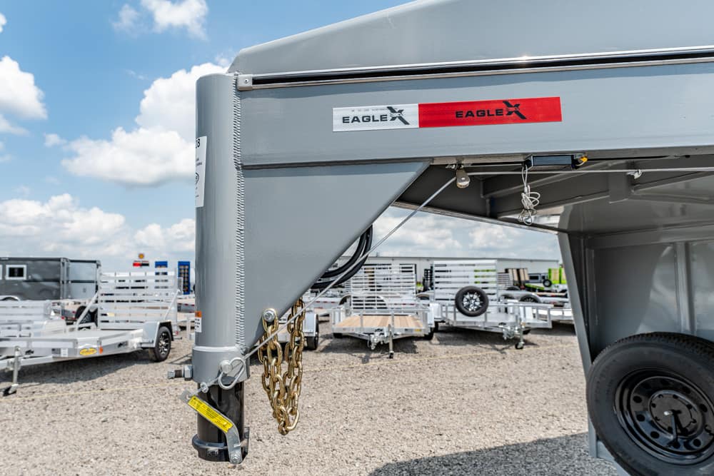Close-up of a grey trailer hitch with chains and a crank, Eagle brand sticker, in a trailer lot.