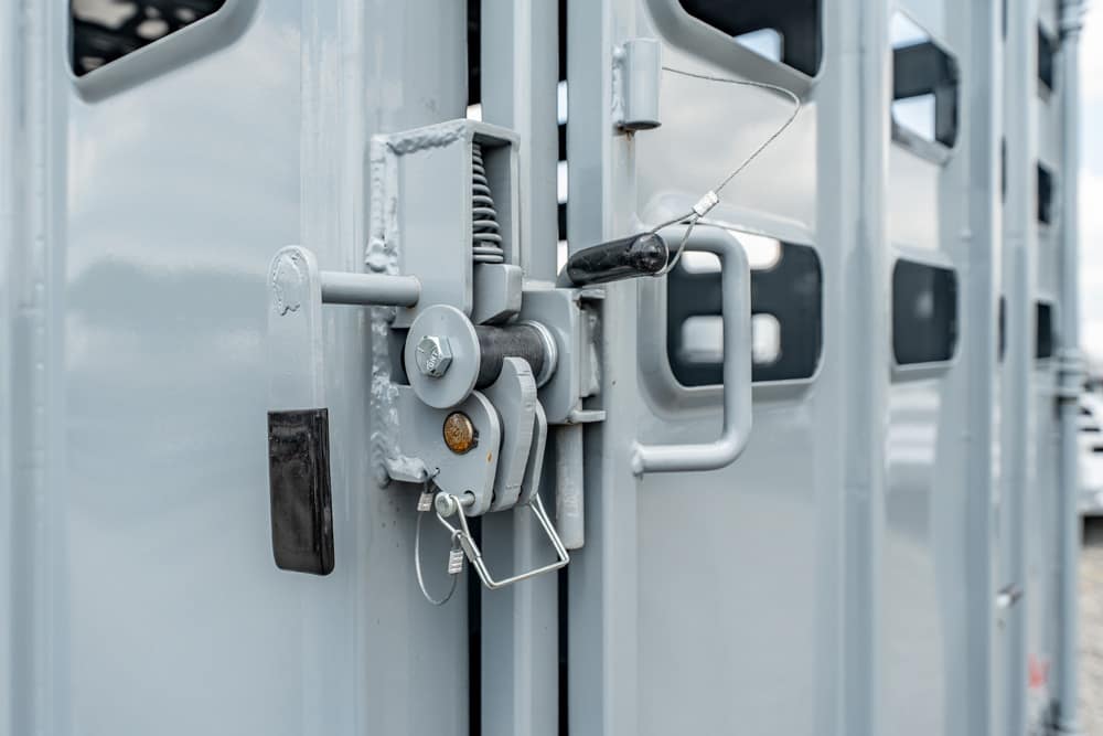 Close-up of a gray metal latch securing double industrial doors with a locking pin and wire.