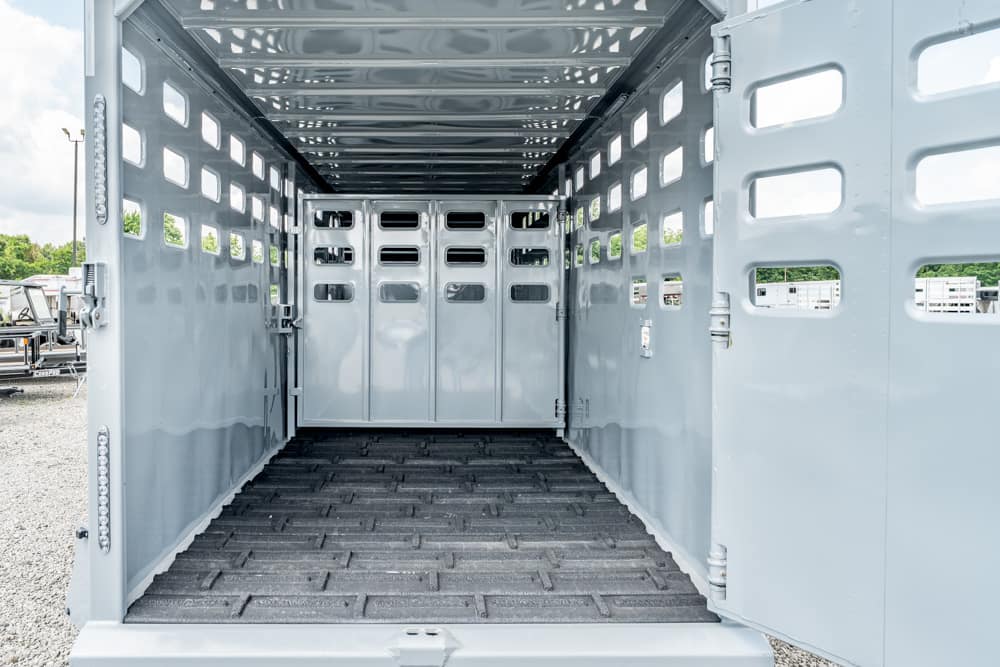 Empty metal livestock trailer interior with dividing gates and ventilation slots along the sides and rear ramp