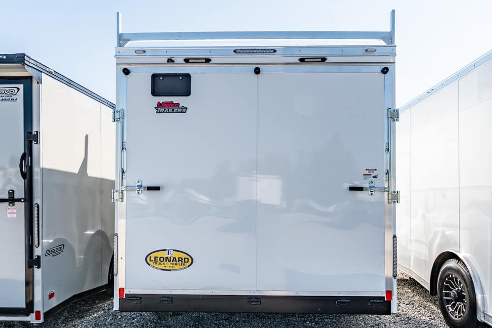 Back of a white enclosed cargo trailer with double rear doors, metal latches, and a Leonard Trailer sticker at the bottom left.
