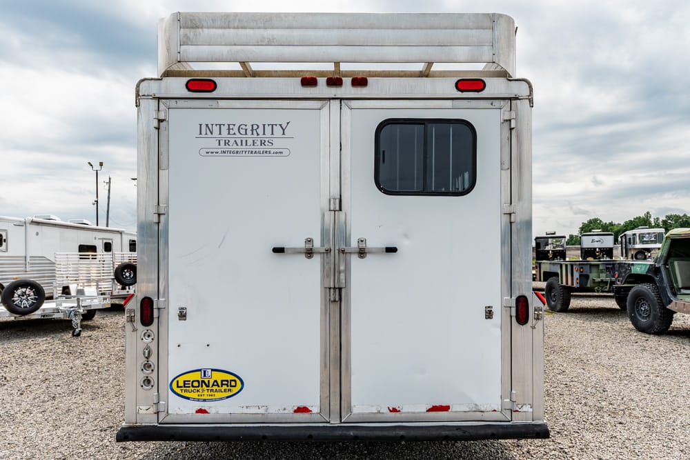 Rear view of a white trailer with metal trim, double doors, and a small window; logos say Integrity Trailers and Leonard Trailer.