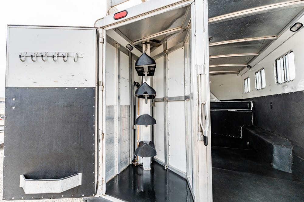 Interior of a utility trailer showing a tall vertical rack with four black funnel-shaped components mounted on a central column, plus open side doors and a dark interior.