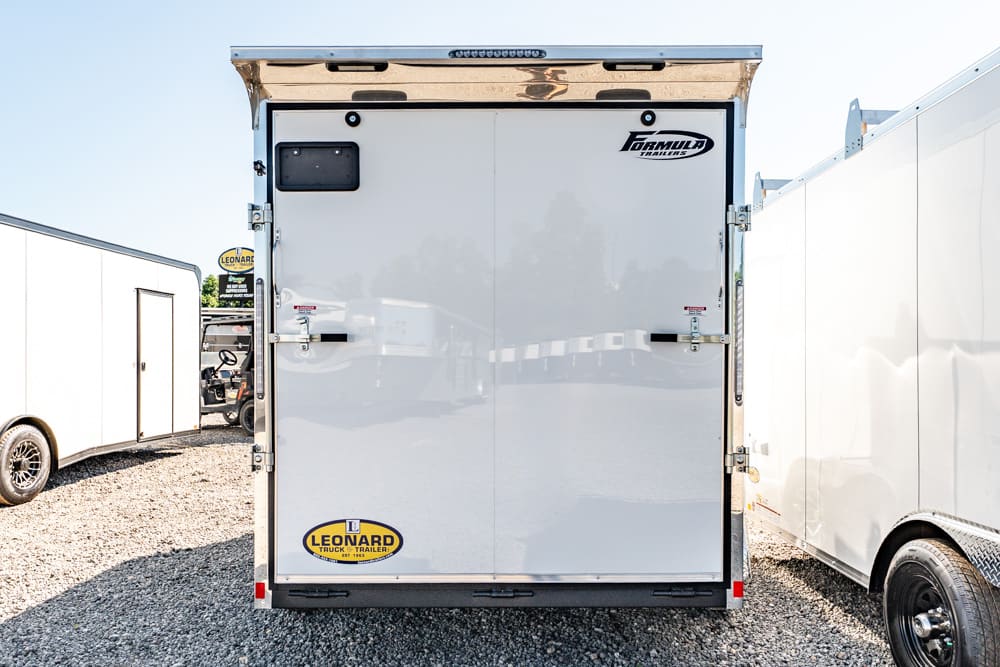 Rear view of a white double-door cargo trailer in a lot, with Leonard logo bottom left and Formula Trailers logo top right.