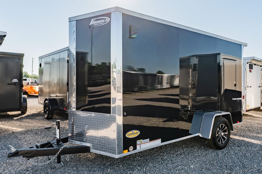 Black enclosed cargo trailer with a silver diamond-plate front, single axle, and a hitch on a gravel lot.