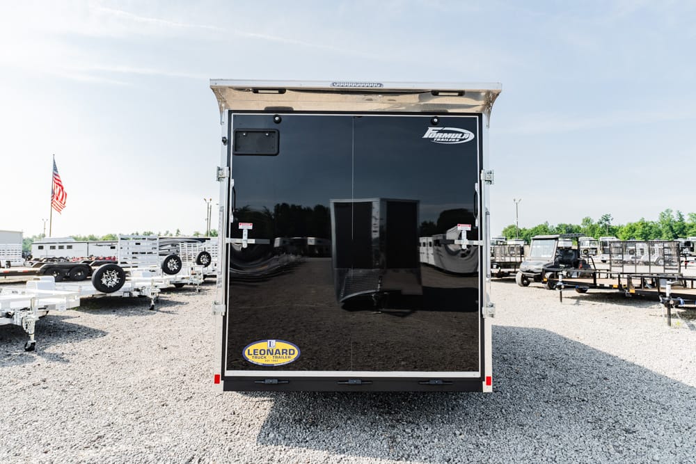 Rear view of a glossy black enclosed cargo trailer with double doors, parked in a dealership lot. Visible logos read 'Leonard' and 'Form…' on the doors, with other trailers and an American flag in the background.