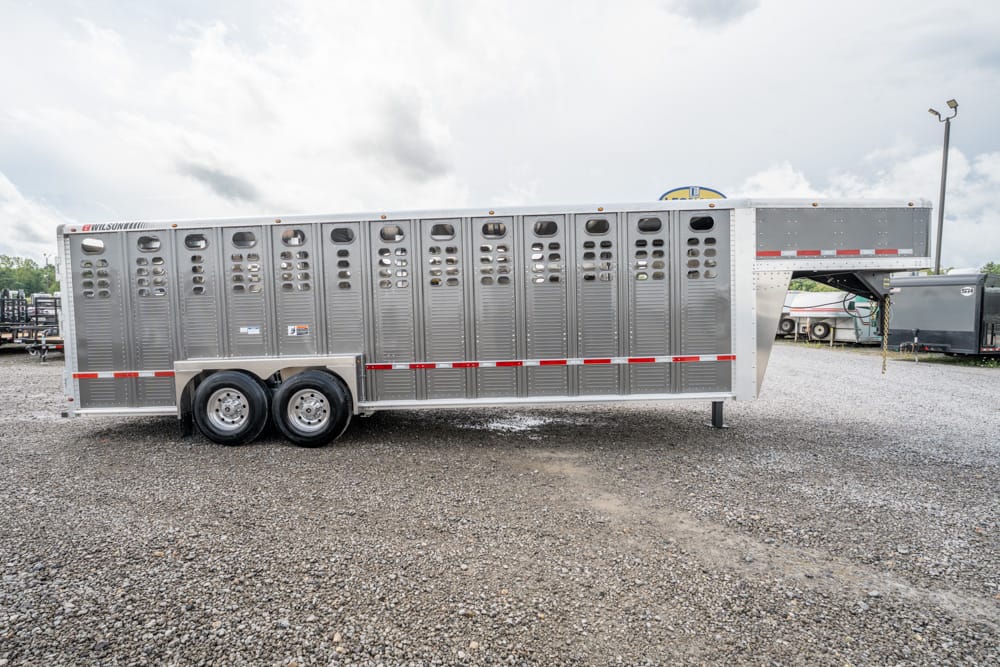 Silver aluminum livestock trailer with multiple ventilation openings, parked on gravel.