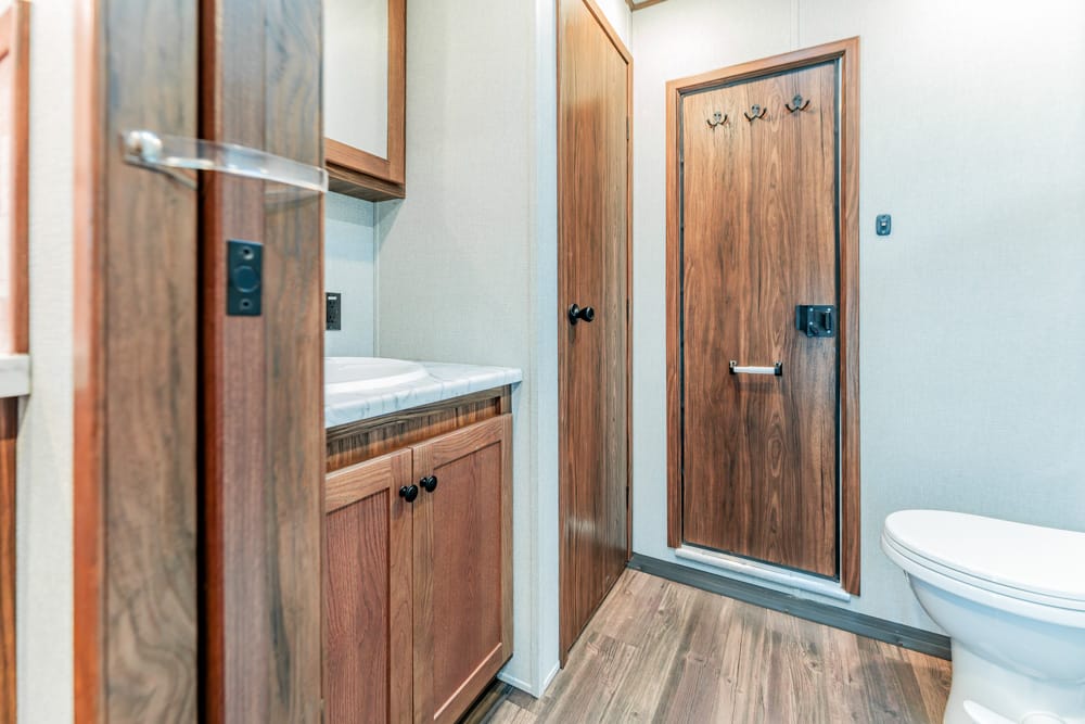 Narrow bathroom with wooden cabinets, a sink and countertop, and a toilet visible on the right.