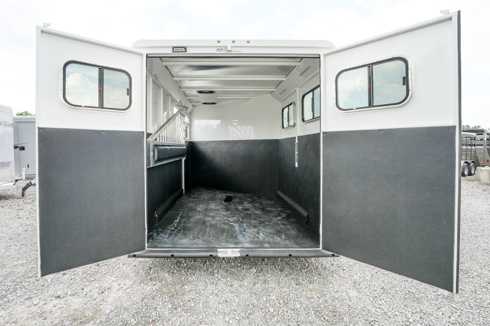 Open horse trailer with clean, empty cargo area and black lower wall panels, viewed from the rear doors.