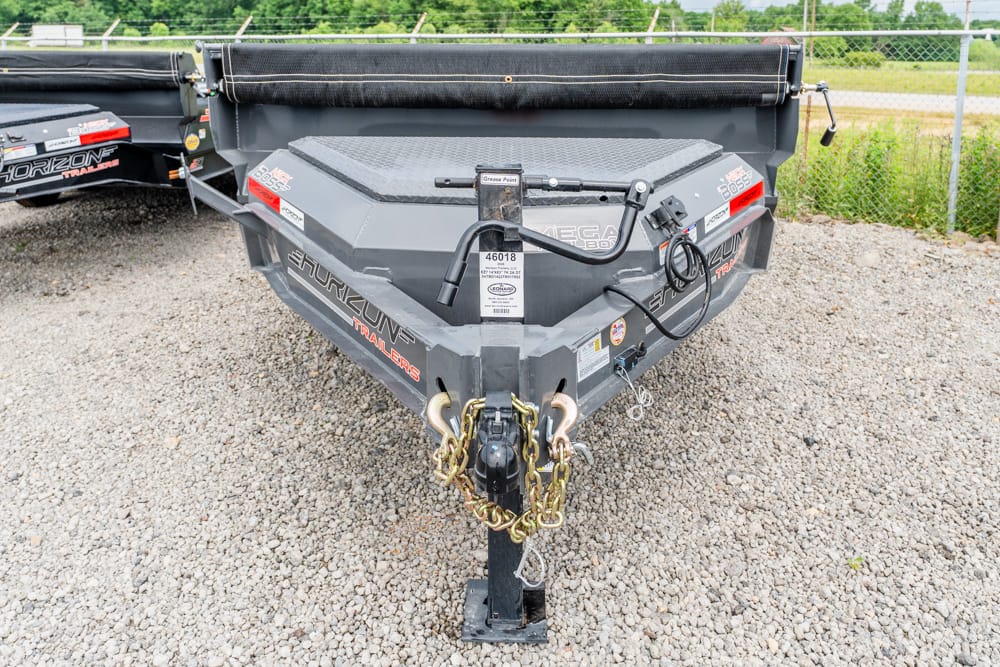 Front view of a gray Horizon Trailers utility trailer with a heavy-duty hitch, safety chains, and a black rolled tarp, parked on gravel in a lot.