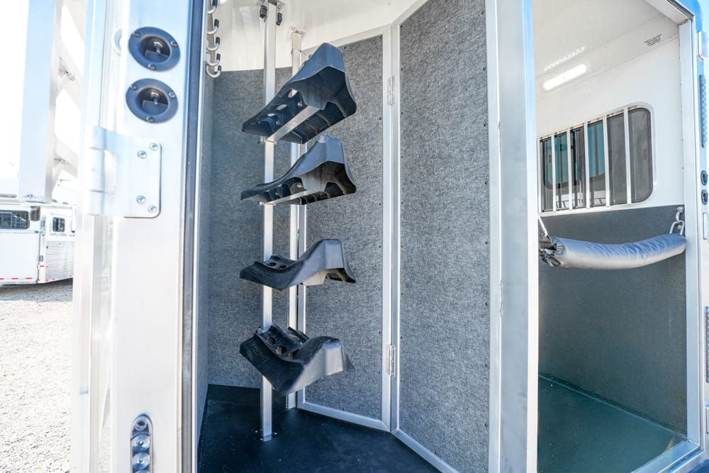 Interior of a trailer showing a vertical rack with four black protective boot shells mounted on a metal pole along the wall.