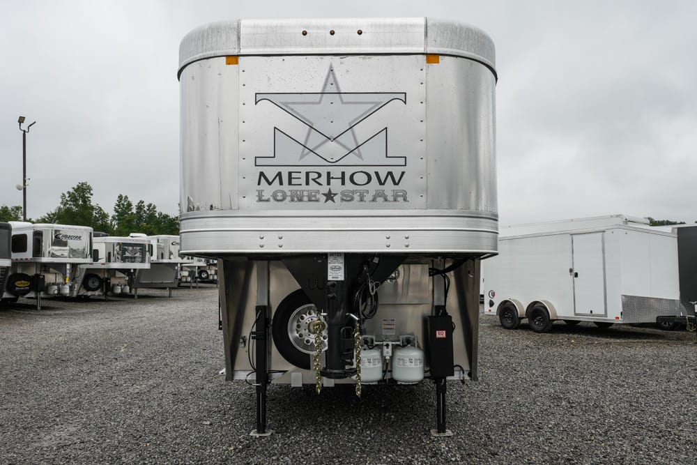 Silver Merhow Lone Star horse trailer parked in a lot with other trailers on a gravel surface.