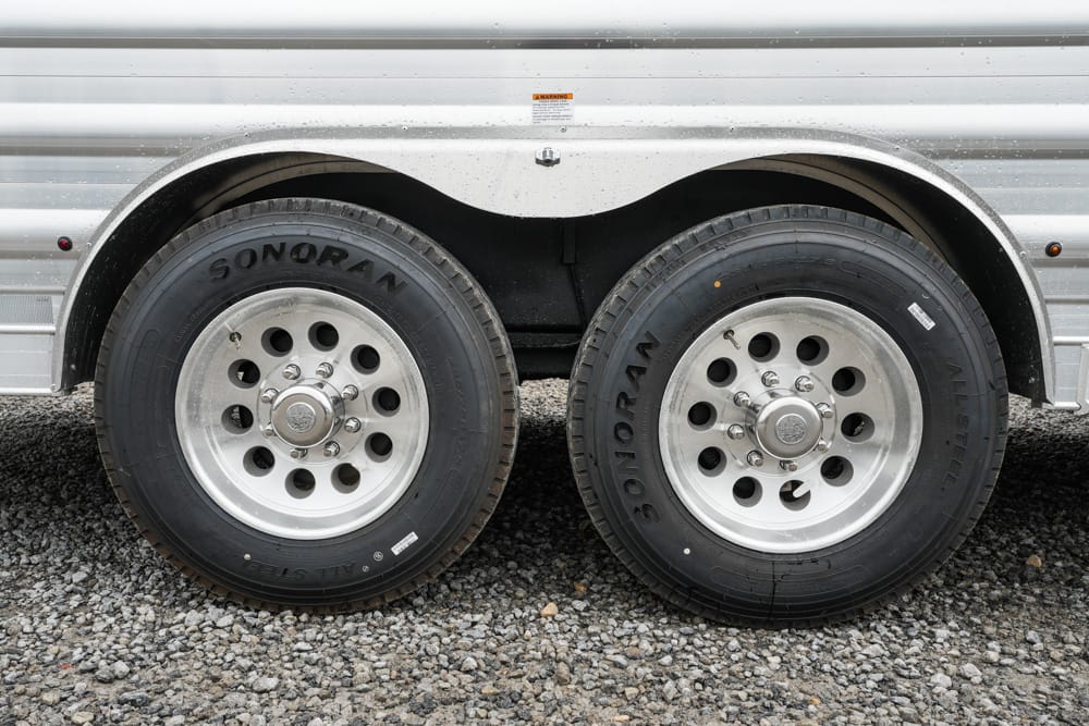 Dual trailer wheels with silver rims on a gravel surface; tires are branded Sonoran.