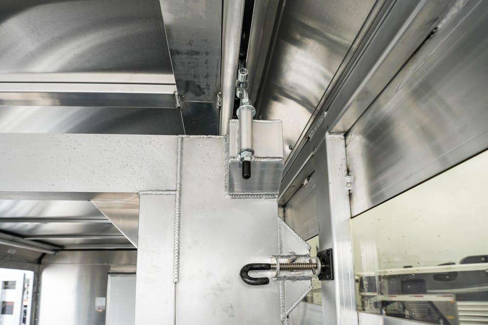 Industrial metal interior showing a lockable door latch on a stainless steel frame with welded seams.