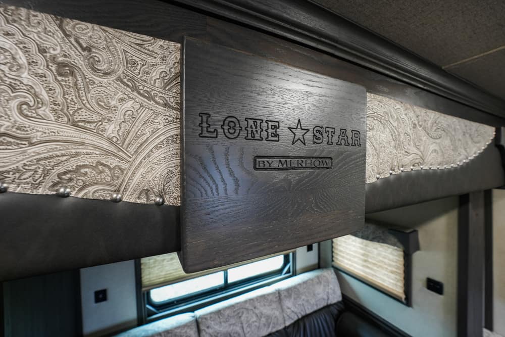 Wooden plaque reads 'Lone Star by Merhow' mounted inside a luxury trailer with dark trim and paisley wallpaper.