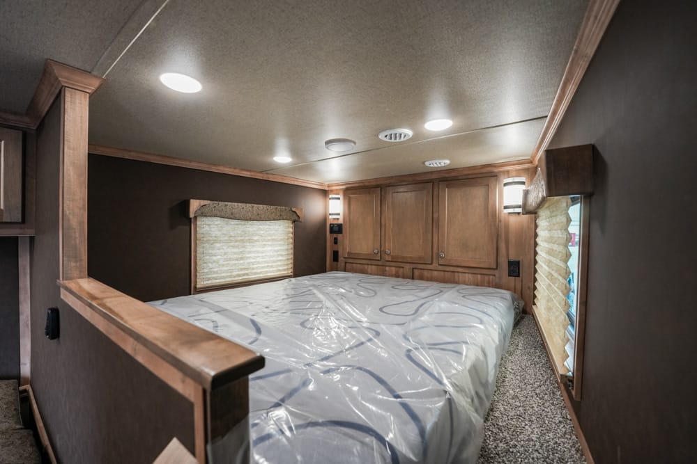 RV bedroom with a large bed, wooden cabinets, and soft ceiling lights
