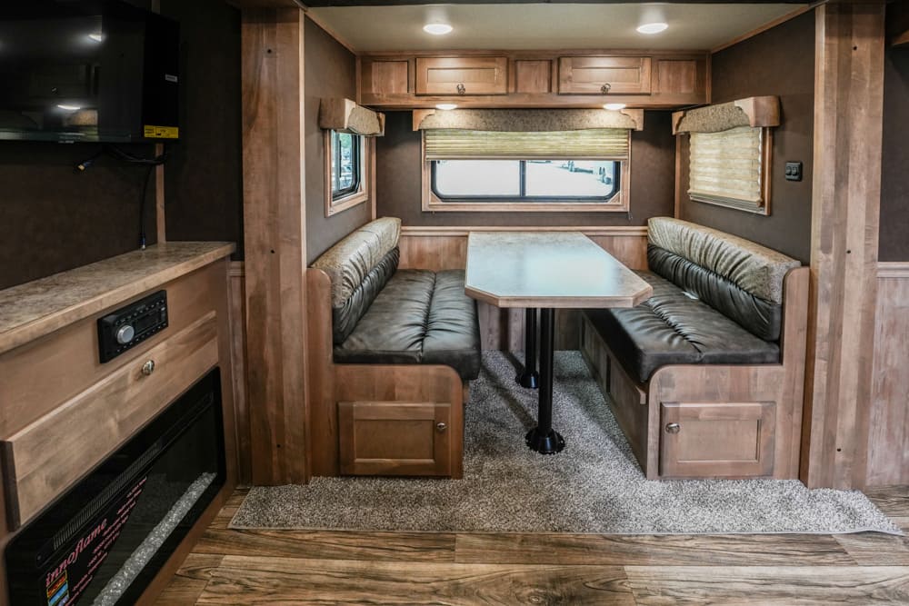RV dining area with L-shaped booth seating, a rectangular table, and overhead cabinets.