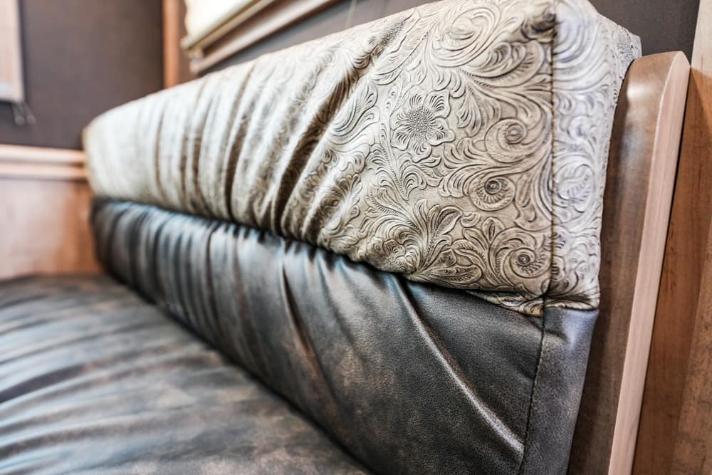 Close-up of a patterned fabric sofa backrest with a dark leather seat and wooden armrest to the side.