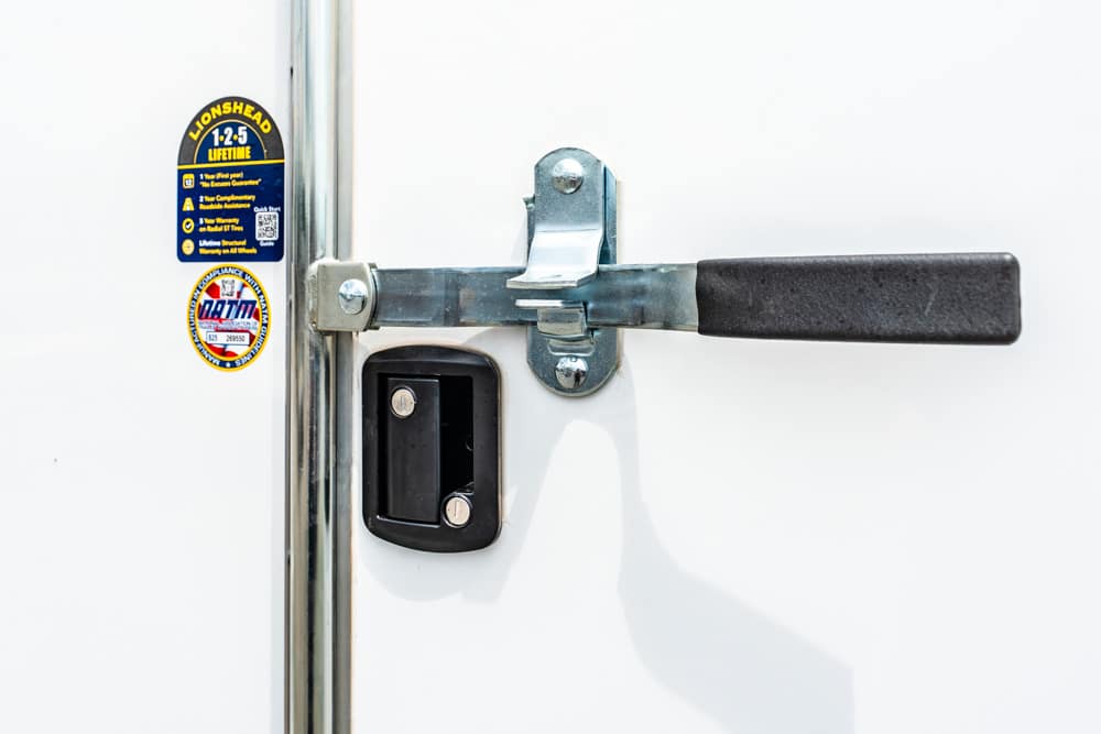 Security door latch bar engaged across a white door with two stickers on the left.